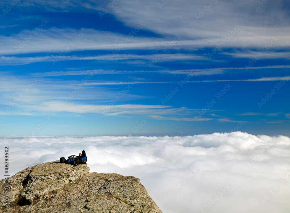 Backpack on the rock over clouds and sky background