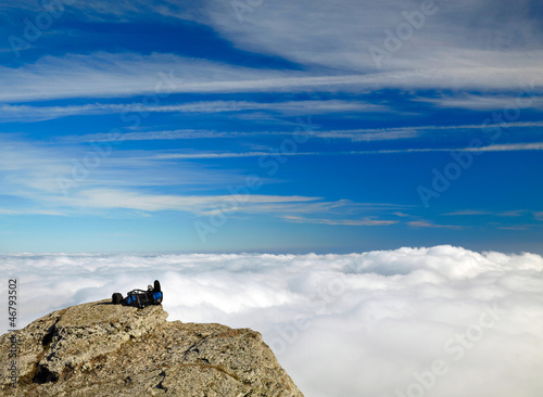 Backpack on the rock over clouds and sky background