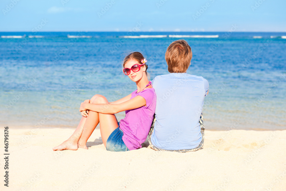 beautiful young couple sitting and having fun on beach