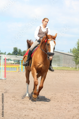 Beautiful young blonde woman riding chestnut horse © virgonira