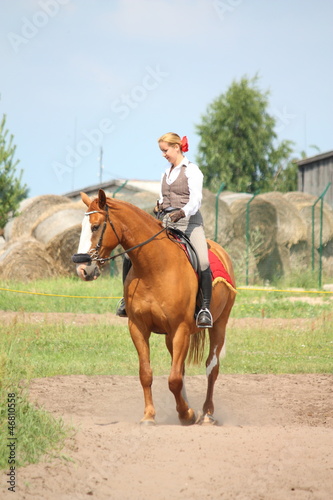 Beautiful young blonde woman riding chestnut horse © virgonira