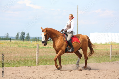 Foto Beautiful young blonde woman riding chestnut horse