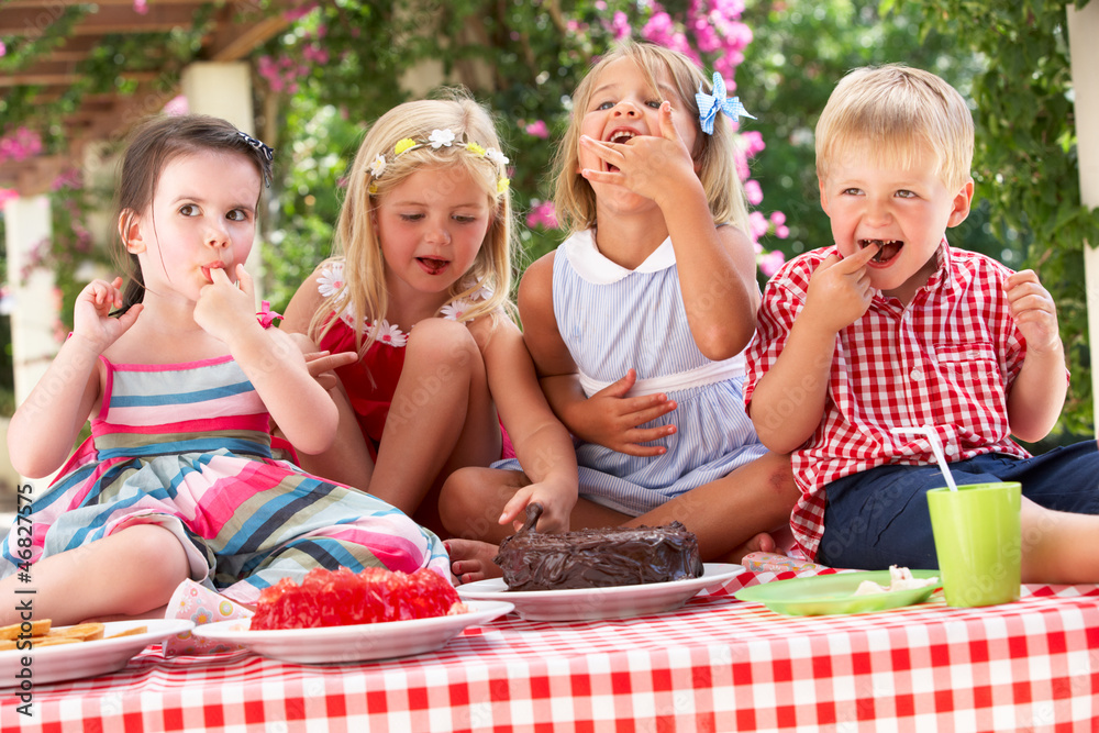 Group Of Children Eating Jelly And Cake At Outdoor Tea Party - obrazy, fototapety, plakaty 