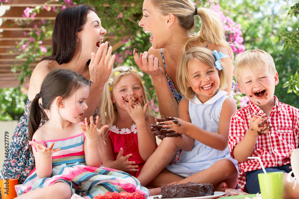 Children And Mothers Eating Jelly And Cake At Outdoor Tea Party