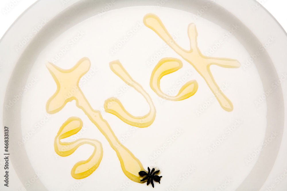 Close-up of stuck written with honey on plate Close-up of stuck written with honey on plate