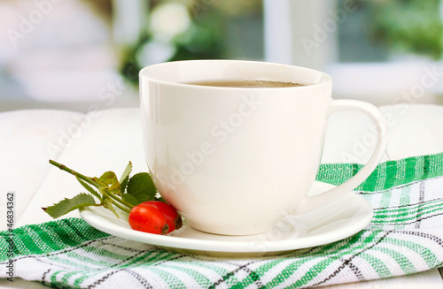 cup of tea with hip roses, on wooden table