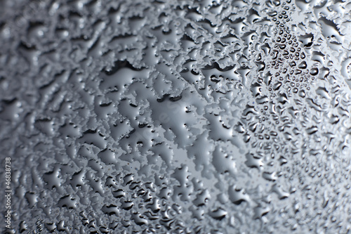 Close-up of water drops on black reflective surface.