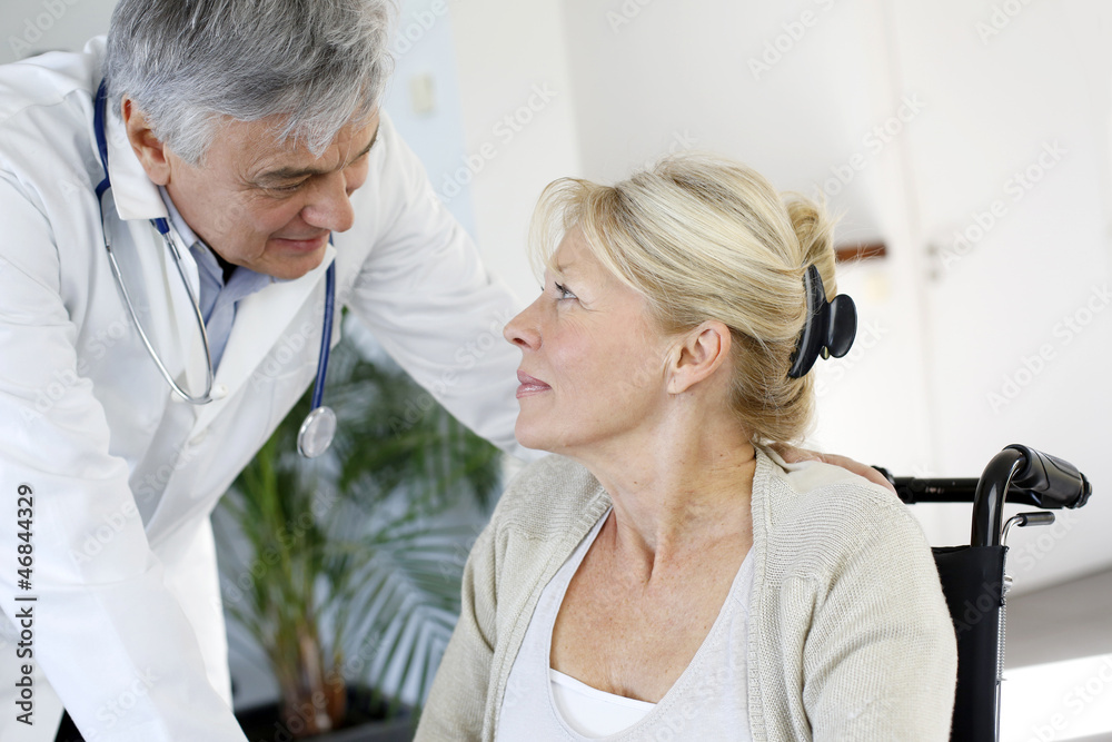 Portrait of surgeon talking to patient in wheelchair