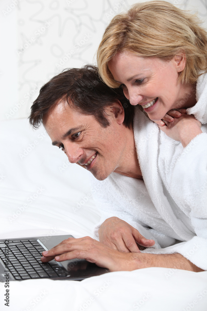 Couple on laptop in dressing gown. Couple on laptop in dressing gown.