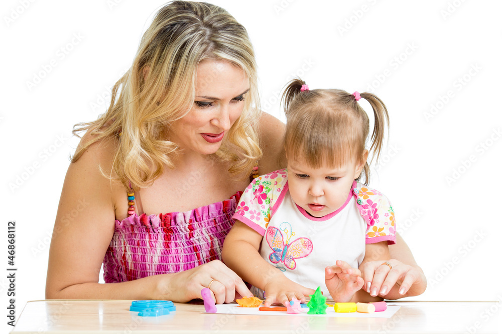 Happy little kid and mother sitting at table and playing with co Happy little kid and mother sitting at table and playing with co