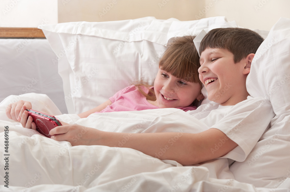 Children in bed playing game console. Close-up. Children in bed playing game console. Close-up.