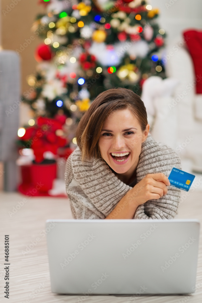 Smiling woman with laptop and credit card near Christmas tree Smiling woman with laptop and credit card near Christmas tree