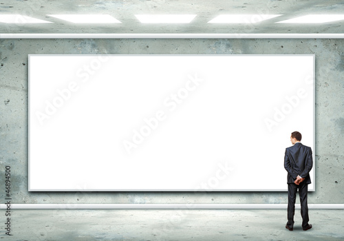 Business person standing near a blank billboard