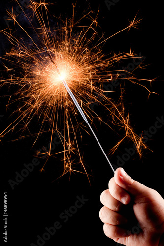 Child's hand, holding a burning sparkler.