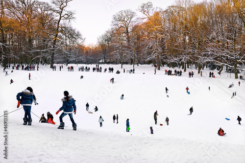 Funny group of children and adults playing in the snow. Park in