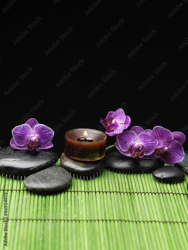 Red four orchid with candle with black stone on green mat Red four orchid with candle with black stone on green mat