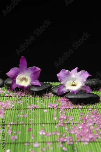 Two pink orchid with zen stone and pile of sea salt on mat