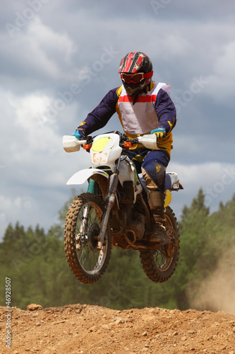 Fototapeta Naklejka Na Ścianę i Meble -  Man wearing in helmet on dirt motorcycle jumps on muddy potholes
