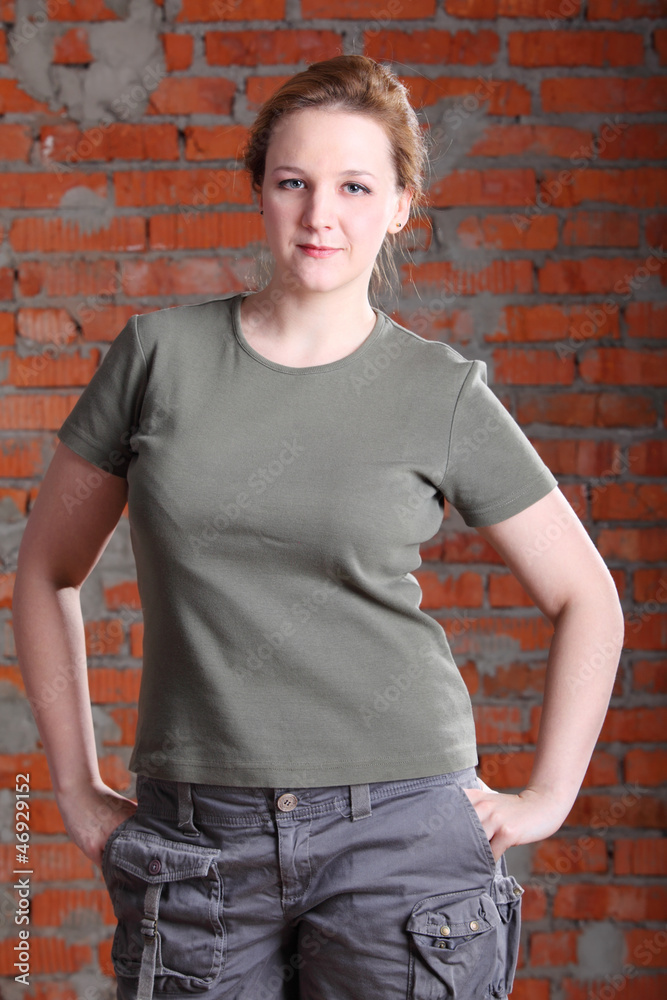 brown-haired woman hold hands in pockets near brick wall brown-haired woman hold hands in pockets near brick wall