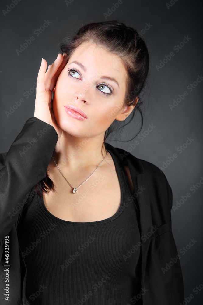 Portrait of beautiful young brunette girl hold her face in coat