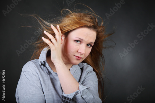 Brown-haired woman hold hair fluttering in wind in photo studio