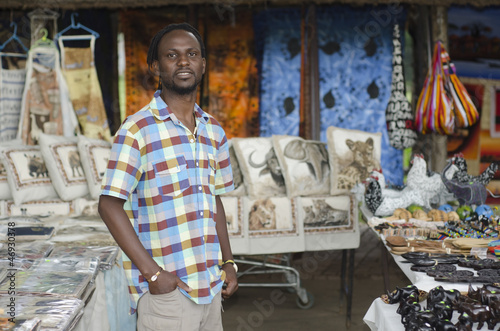 african curio salesman vendor  in front of wildlife items photo