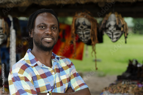 African curio salesman vendor in front of ethnic masks