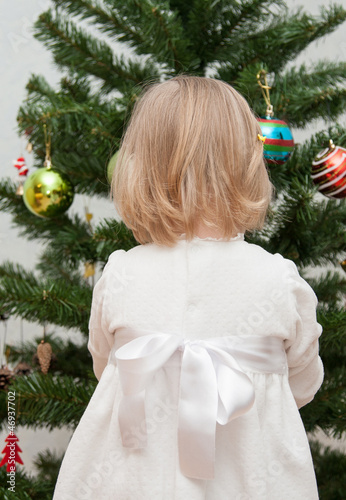 Adorable little girl decorating a Christmas tree