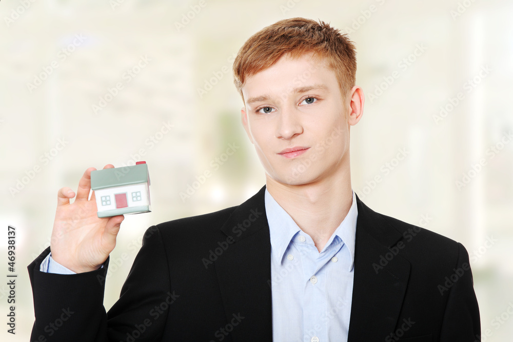 Young business man holding house model Young business man holding house model