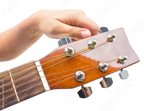 Hand tuning a guitar from headstock isolated on white background