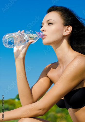 Beautiful brunette girl drinking from a bottle of water