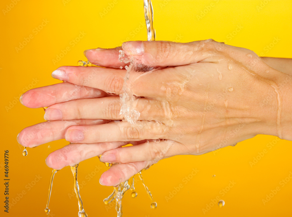 Fototapeta premium Washing hands on orange background close-up