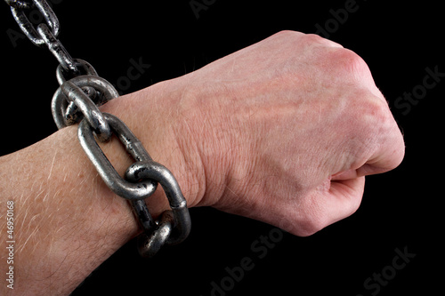 Hand in fist and shackles, black background