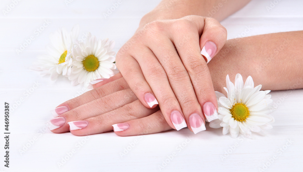 Fototapeta premium Woman hands with french manicure and flowers