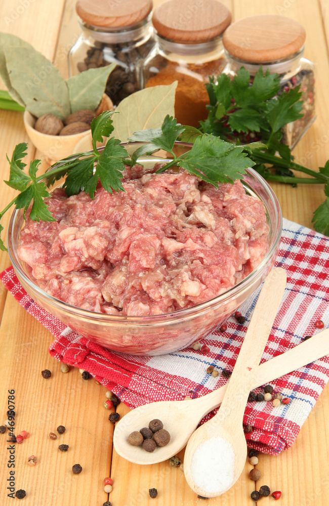 Bowl of raw ground meat with spices on wooden table Bowl of raw ground meat with spices on wooden table