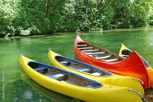 Photography Four empty plastic canoes in turquoise green river