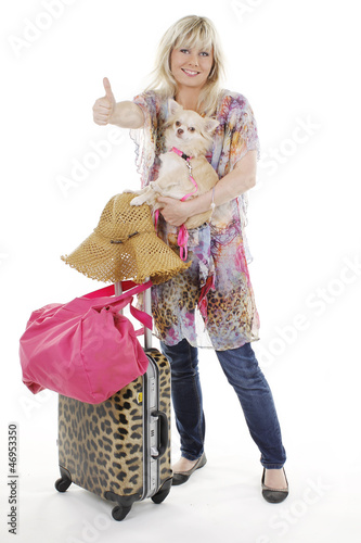 Hübsche Frau mit Gepäck und Hund hält Daumen hoch
