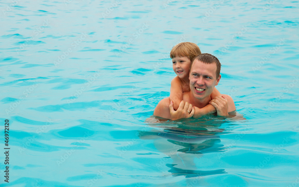 The happy child swimming with the father in the sea