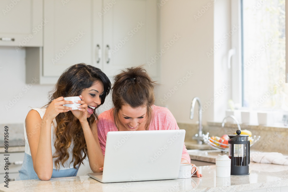 Happy women having coffee while looking at a laptop Happy women having coffee while looking at a laptop