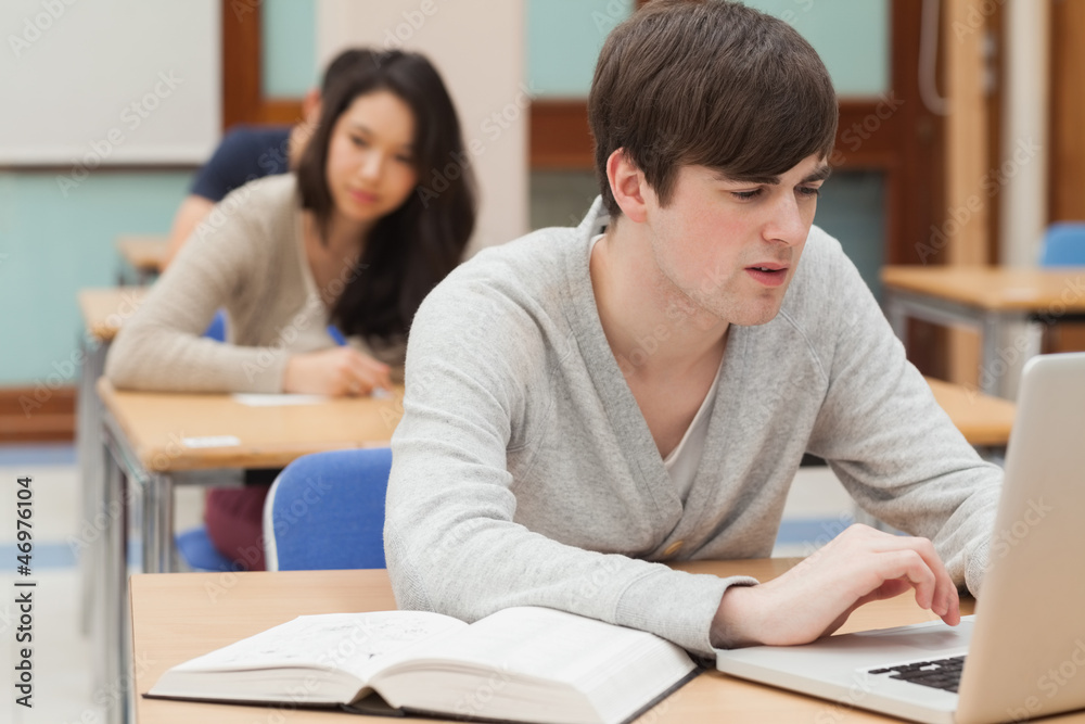 Student sitting at the classroom while typing Student sitting at the classroom while typing
