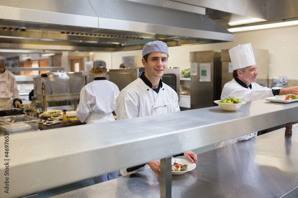 Obraz premium Smiling chef garnishing a salad