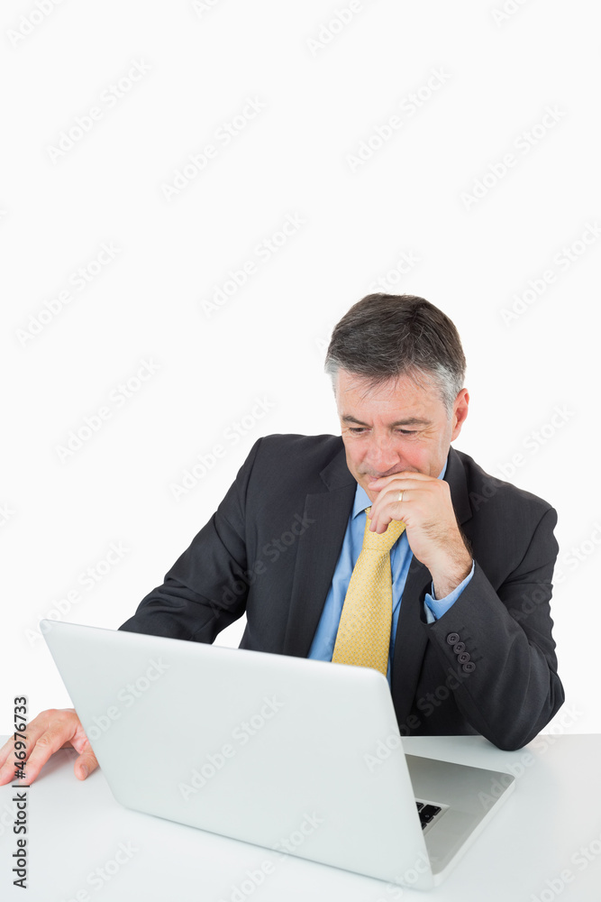 Thoughtful man sitting at his desk with laptop Thoughtful man sitting at his desk with laptop