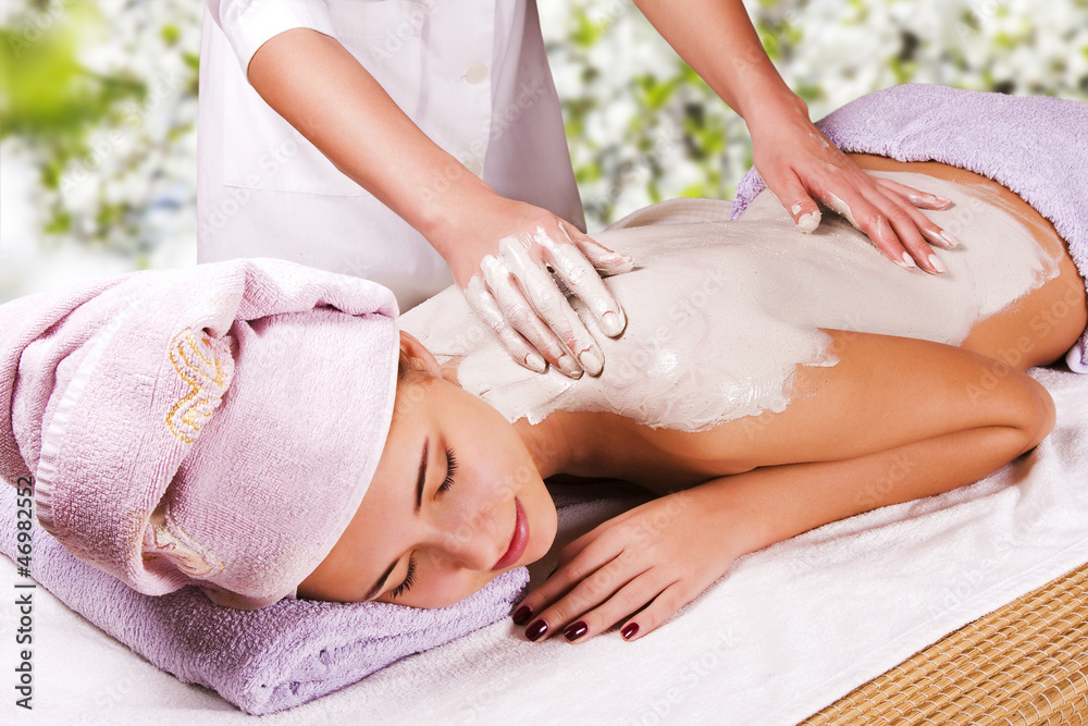 Young woman with slimming body thermal mask on her back. Spa Tre