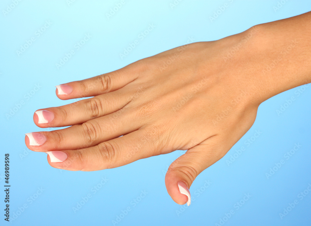 Beautiful woman's hand with french manicure on blue background