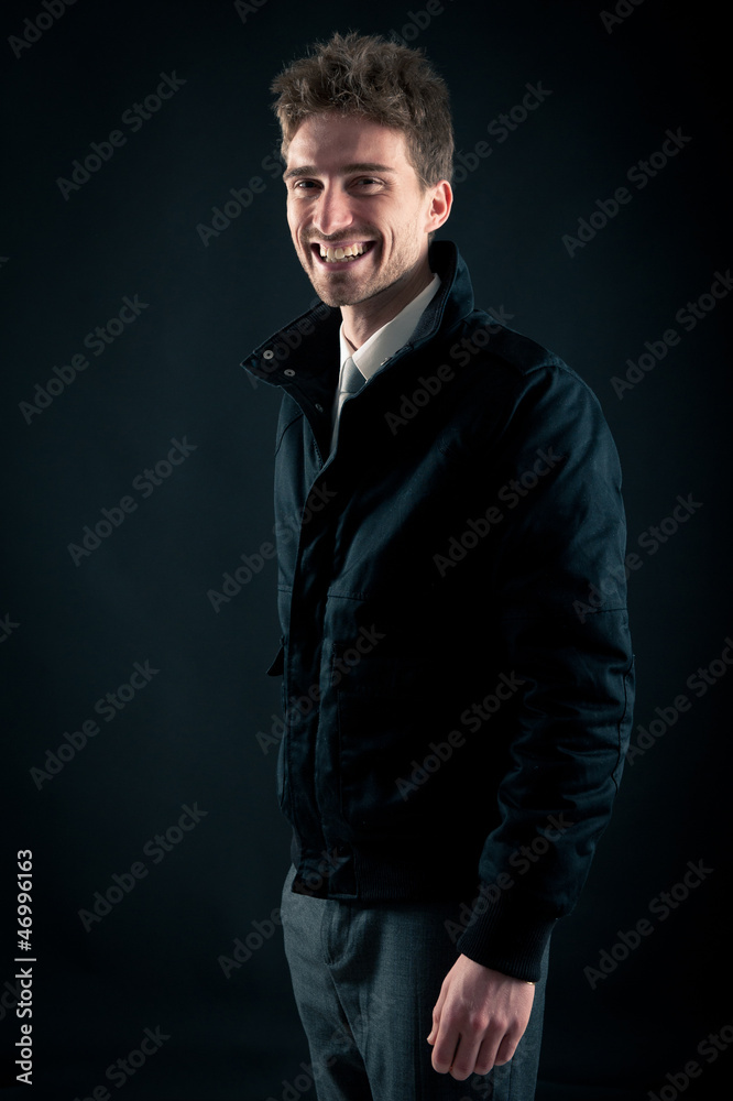 Portrait of handsome, smiling man against dark background.