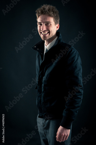 Portrait of handsome, smiling man against dark background.