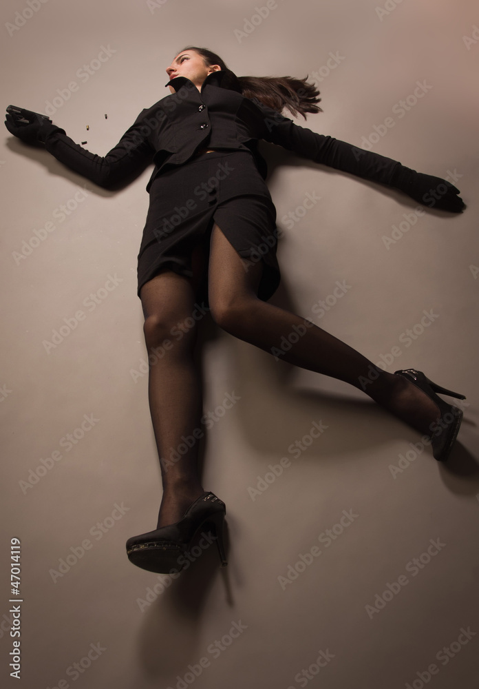 Woman in a black suit with gun lying on the floor