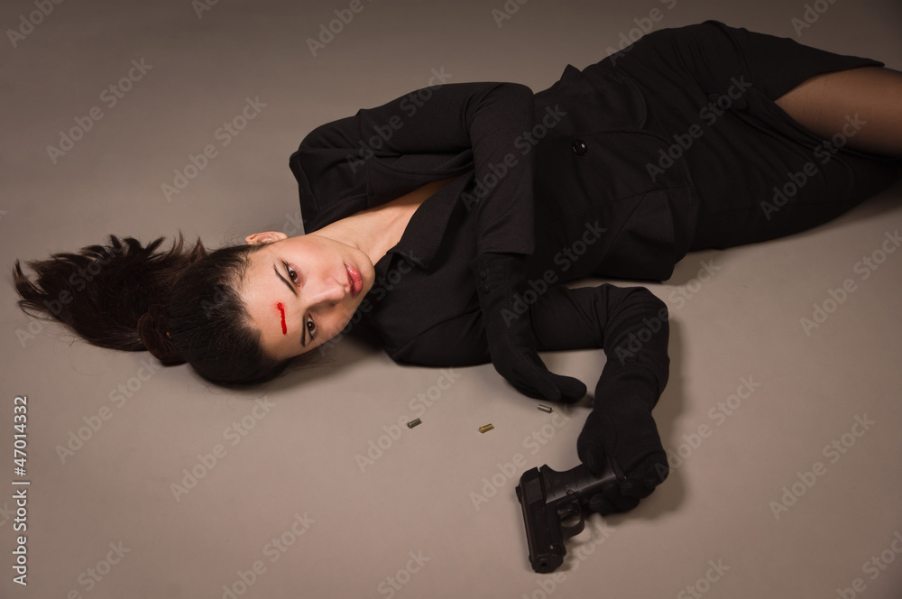 Woman in a black suit with gun lying on the floor Woman in a black suit with gun lying on the floor