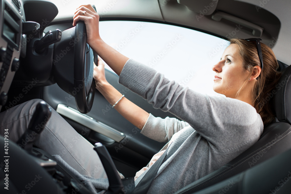 Pretty young woman driving her new car