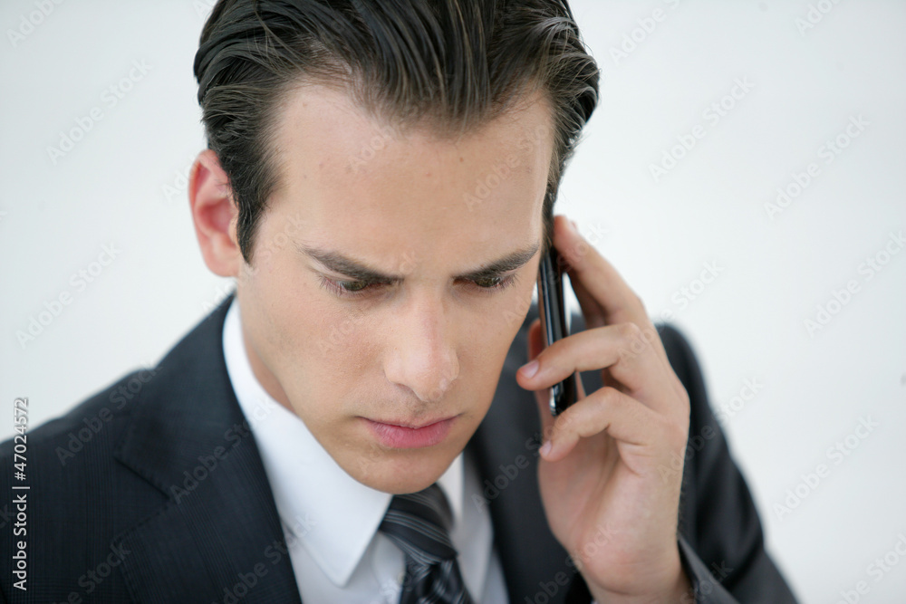 A concerned businessman talking on his mobile phone A concerned businessman talking on his mobile phone